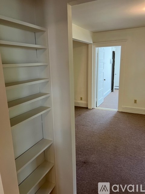 A hallway with a carpeted floor and a white door at the end.