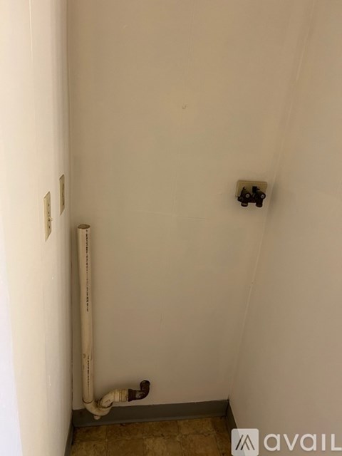 A bathroom with a white wall and a pipe running along it.