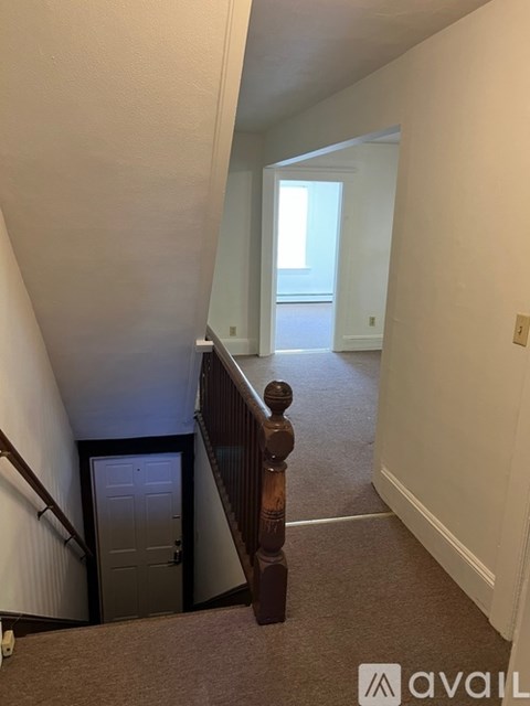 A hallway with a carpeted floor and a door at the end.
