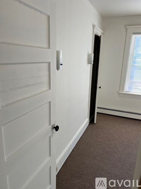 A white door with a black handle and a white wall.