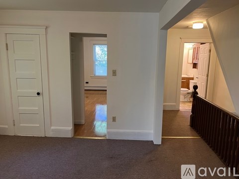 A room with a white door and a window with a view of trees outside.
