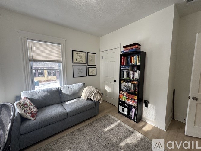 A living room with a grey couch and a bookshelf filled with books.