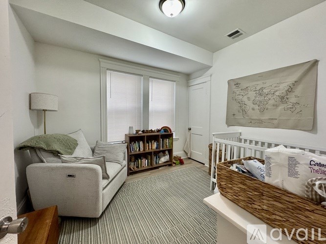 A bedroom with a white couch, a white bed, and a white wall.