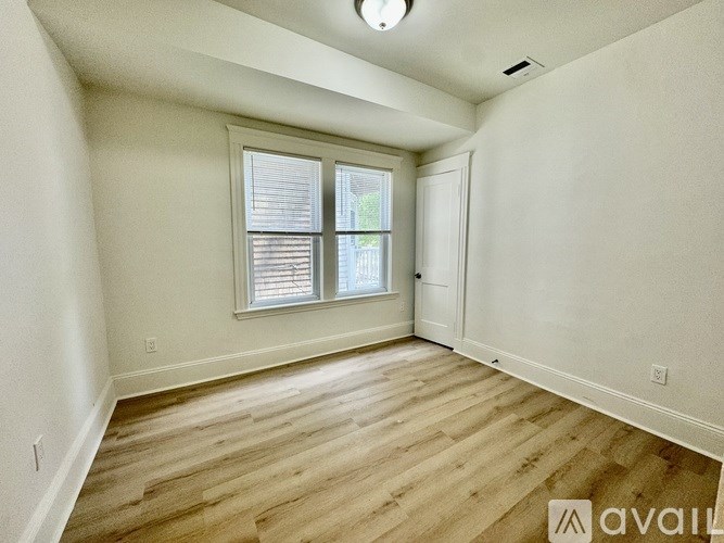 A room with wooden flooring and a window with blinds.