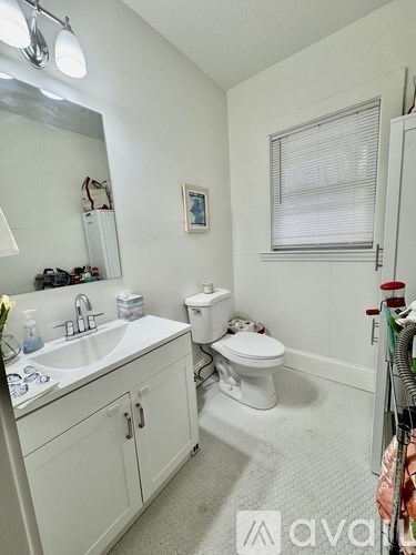 A white bathroom with a toilet, sink, and mirror.