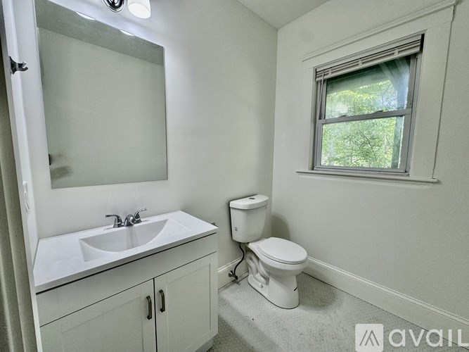 A bathroom with a toilet, sink, and mirror.