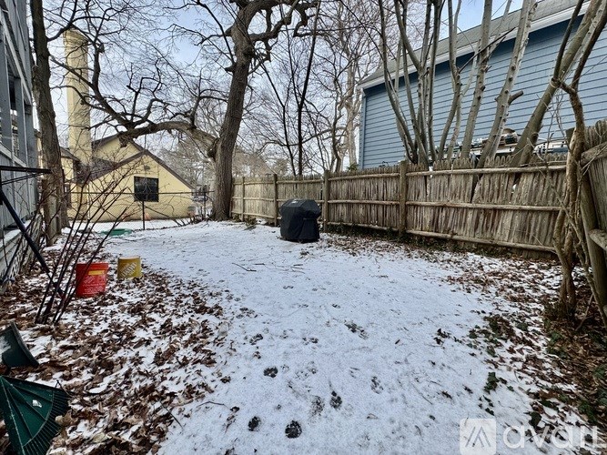 A snow-covered backyard with a fence and trees.