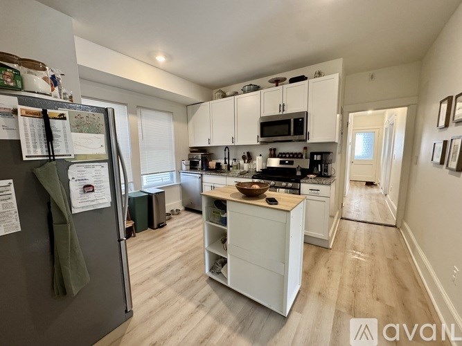 A kitchen with white cabinets and a black fridge.