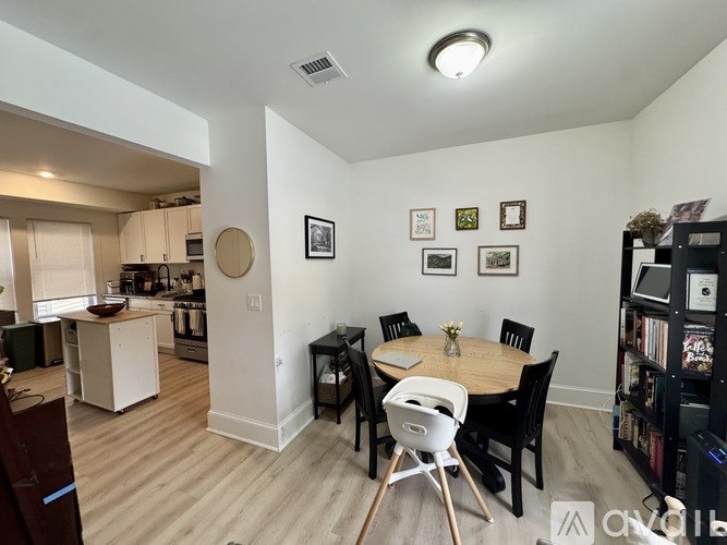 A dining room with a table set for four and a kitchen area in the background.