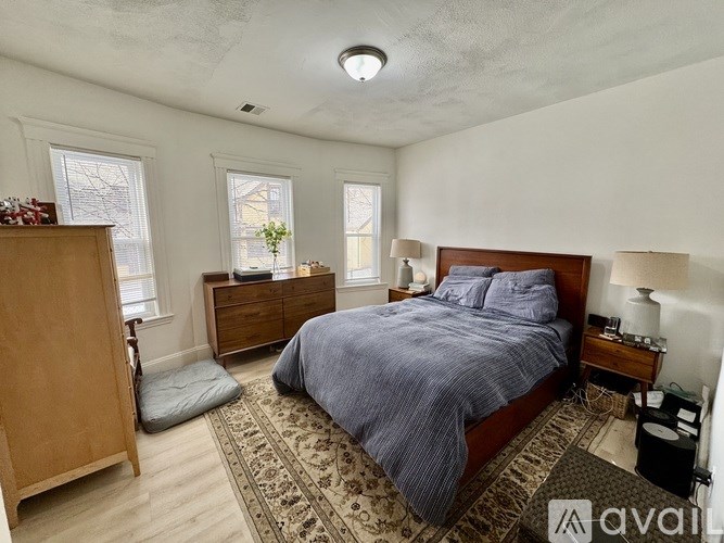 A bedroom with a bed, nightstand, and window.