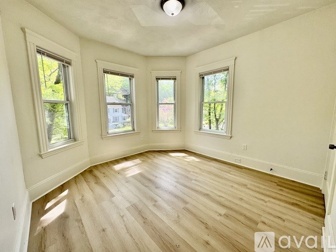 A room with wooden flooring and three windows.