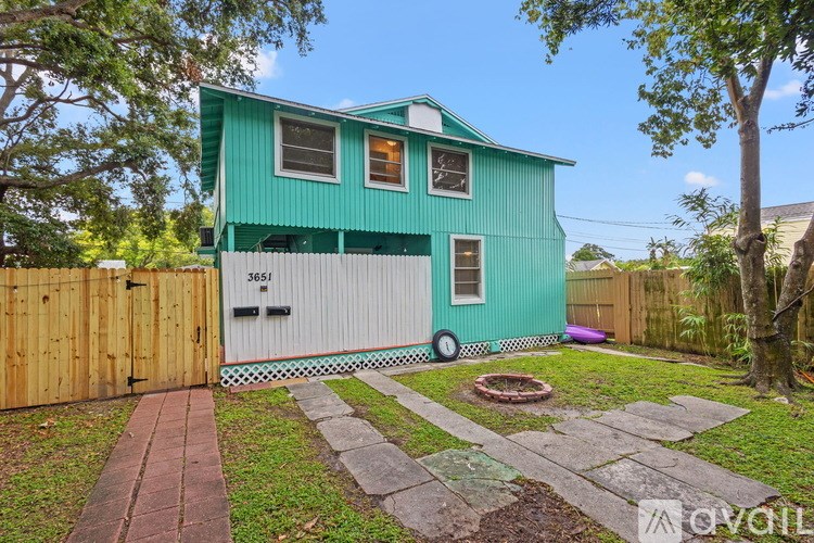 A green house with a white garage door and a wooden fence.