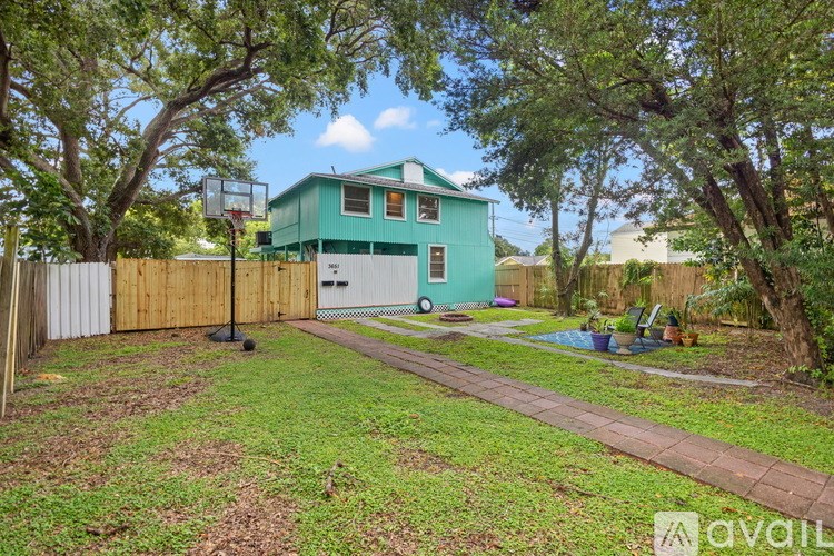 A backyard with a basketball hoop and a green house.
