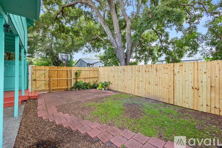 A backyard with a wooden fence and a brick pathway.