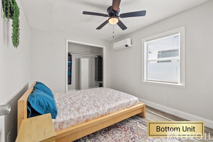 A bedroom with a bed, a ceiling fan, and a window.