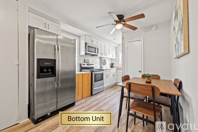 A kitchen with a refrigerator, oven, microwave, and a dining table with chairs.