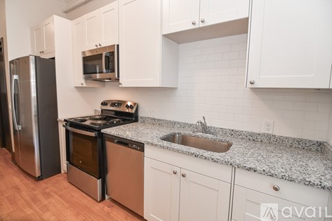 A kitchen with white cabinets and a granite countertop.
