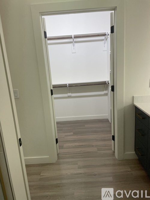 A white door with a black handle is open to a room with a grey floor.