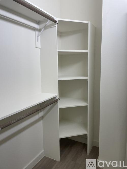 A white shelving unit with four shelves is mounted on a white wall.