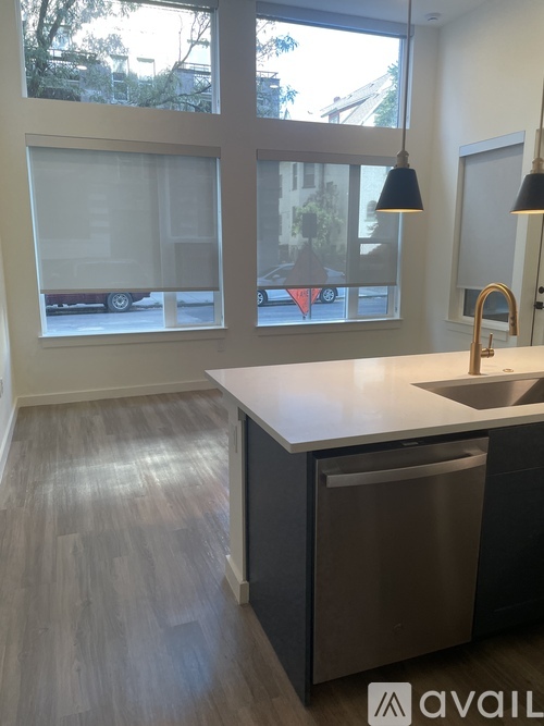 A kitchen with a white counter top and a grey trash can.