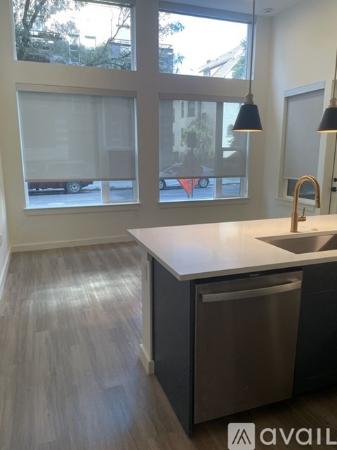 A kitchen with a white counter top and a grey trash can.