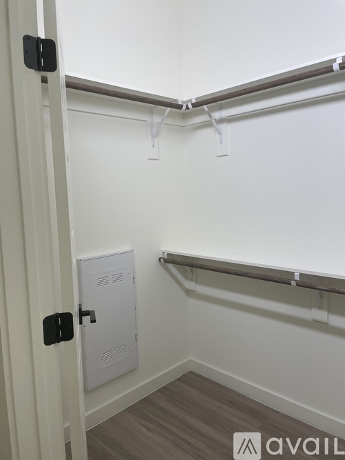 A white door with a black handle is open to a small room with a white cabinet and a white shelf.