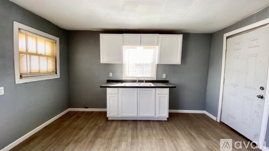 A kitchen with a white cabinet and a window with blinds.