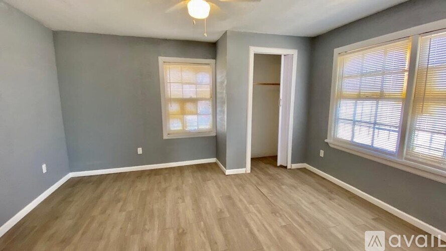 A room with a ceiling fan and two windows.