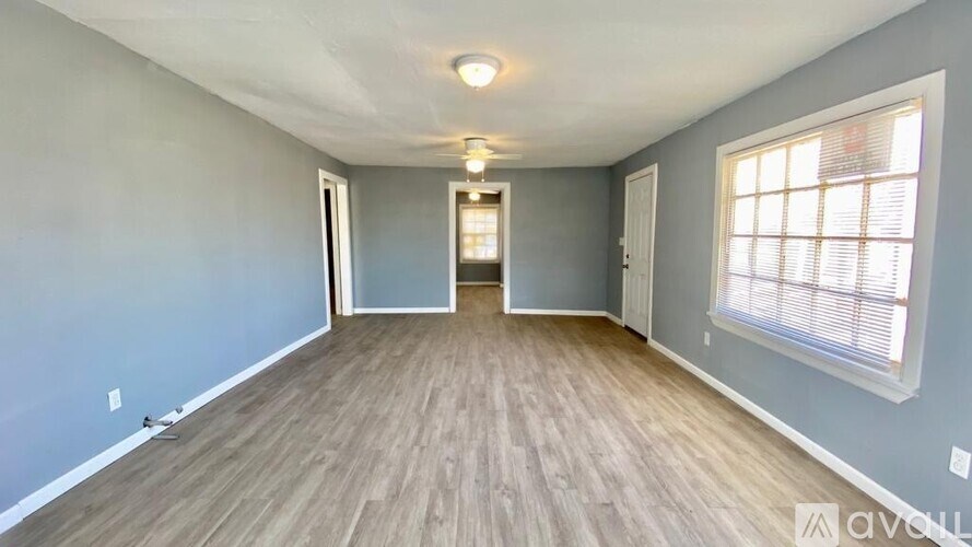 A room with wooden flooring and a window on the right side.