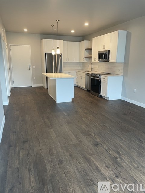 A kitchen with white cabinets and a wooden floor.