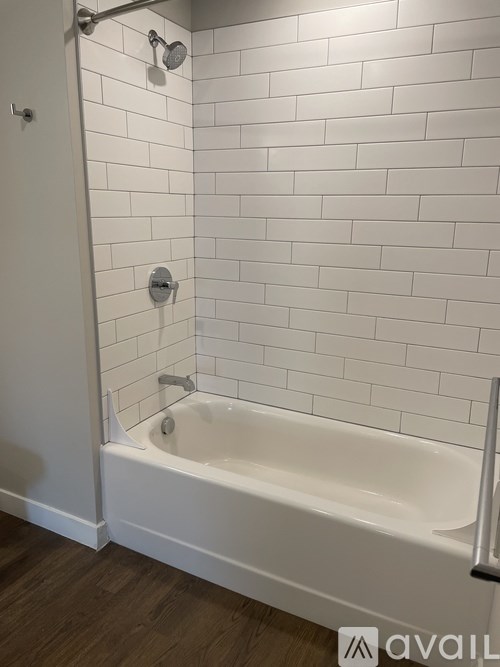A white tiled bathroom with a white bathtub and a towel rack.