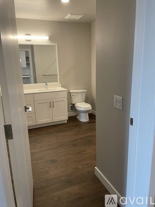 A bathroom with a toilet, sink, and mirror.