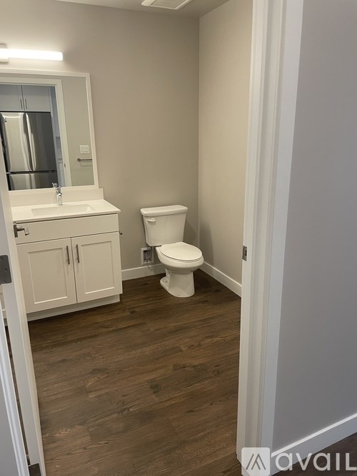 A white toilet sits in a small bathroom with a white sink and cabinet.