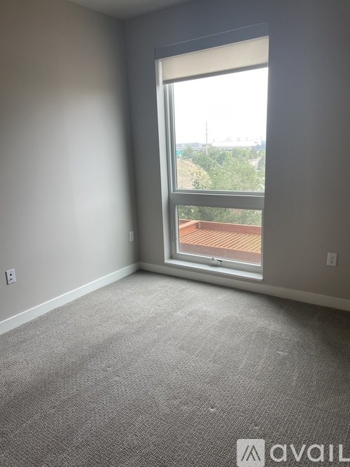A room with a carpeted floor and a large window overlooking a balcony.