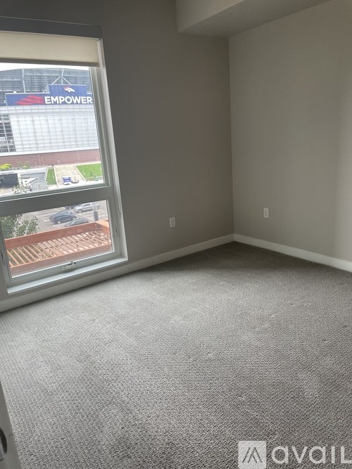 A carpeted room with a window overlooking a parking lot.