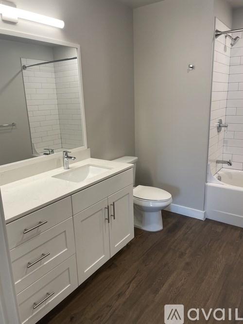A bathroom with a white sink, toilet, and wooden floors.