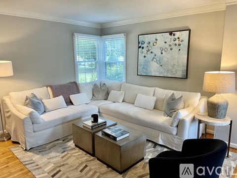 A living room with a white sofa, a grey coffee table, and a large abstract painting on the wall.