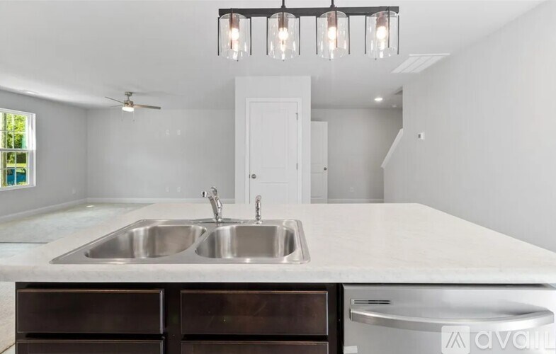 A modern kitchen with a white countertop and a stainless steel sink.