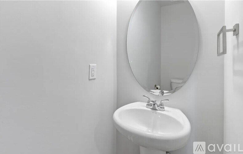 A white sink in a bathroom with a round mirror above it.