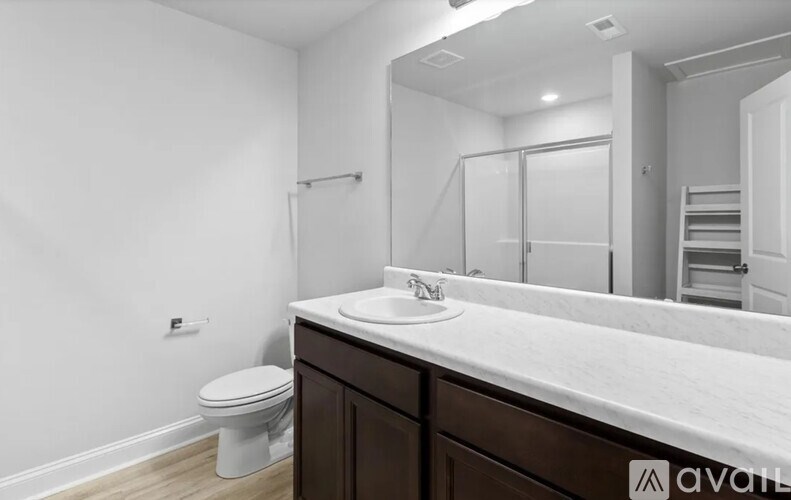 A bathroom with a toilet, sink, and mirror.