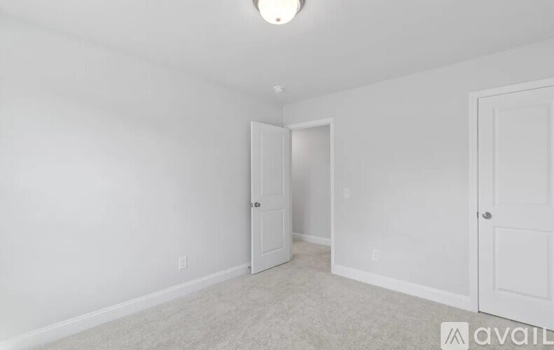 A room with white walls and a carpeted floor with two doors.