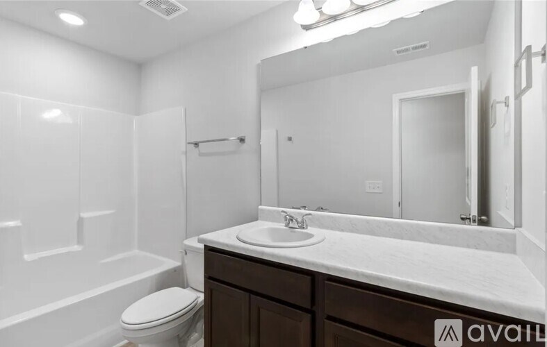 A bathroom with a toilet, sink, and mirror.