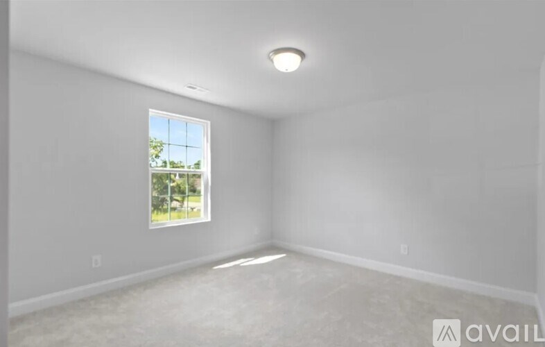 A room with a window and a carpeted floor.