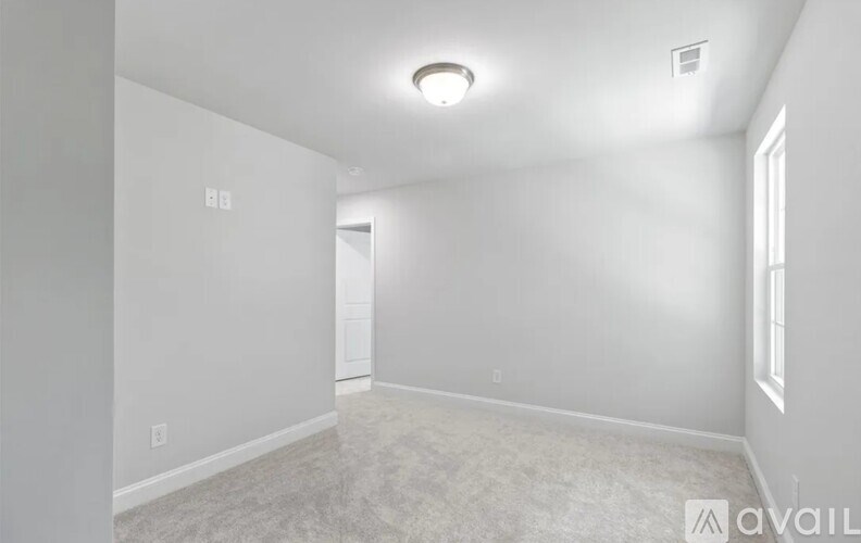 A spacious, empty room with white walls and carpeted floor.