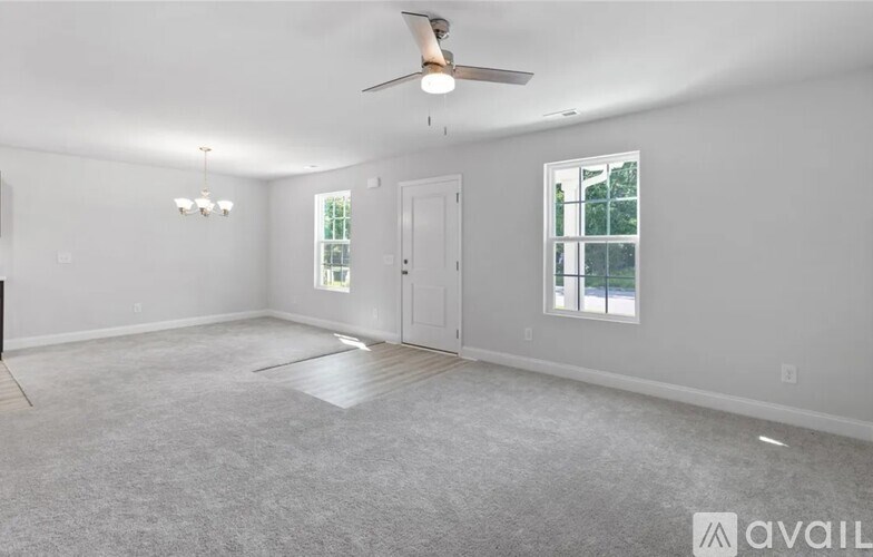 A spacious room with a ceiling fan and two windows.