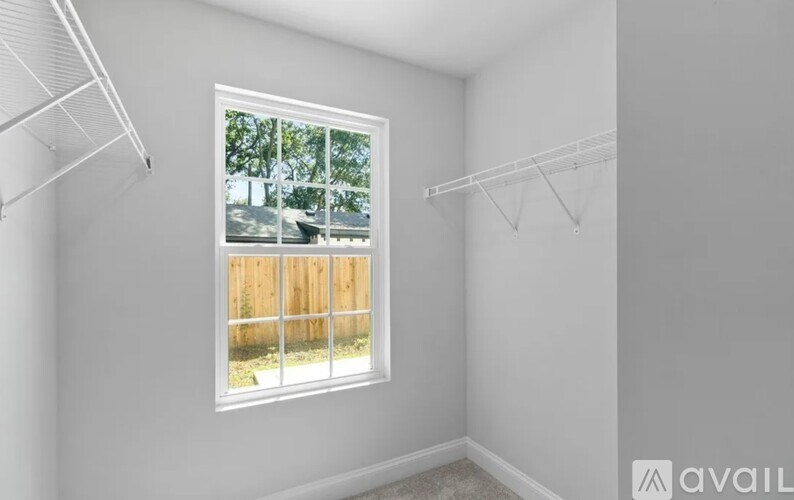 A room with a window showing a wooden fence and trees outside.