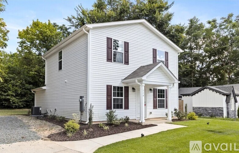 A white house with a black roof and a small front porch.