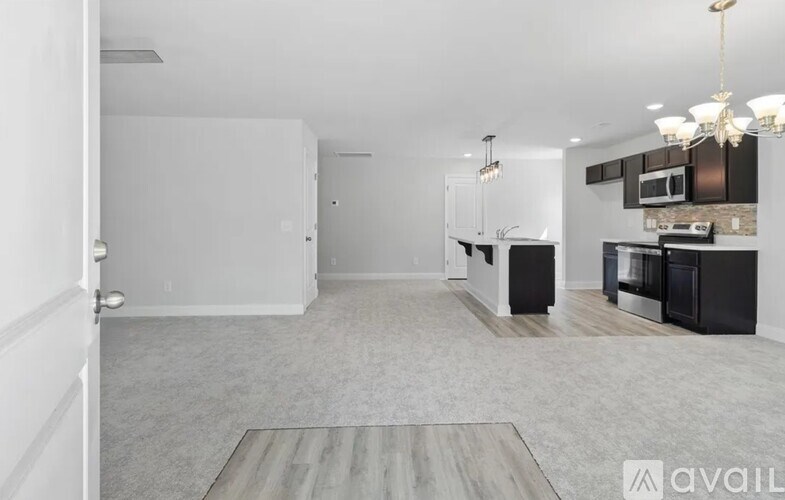 A spacious kitchen and living room with modern appliances and a chandelier.