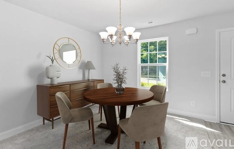A dining room with a round mirror, a wooden table, and chairs.