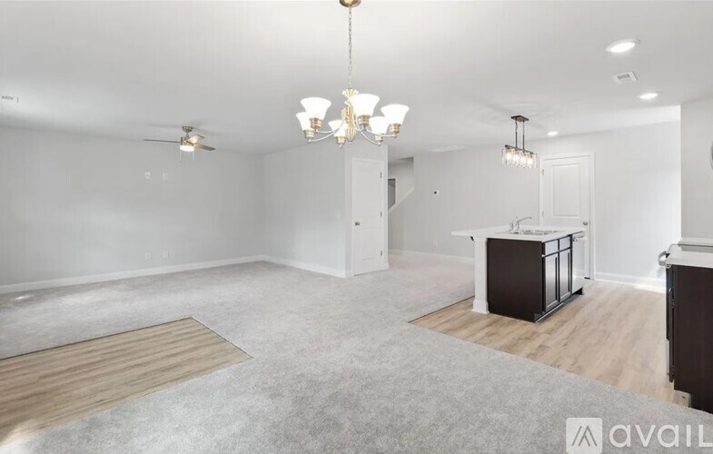 A spacious living room with a kitchen area in the background.